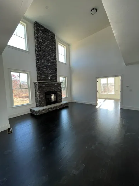 Cathedral living room with stacked stone fireplace and dark hardwood floors